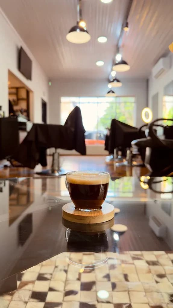 Xícara de café expresso sobre o balcão da Casa do Homem, com as cadeiras da barbearia ao fundo